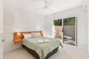 Dormitorio blanco con cama y puerta corredera de cristal en 8 Aqua Promenade Cross the Road to the Beach, en Sunrise Beach
