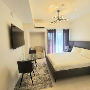 1 dormitorio con cama, mesa y TV en INSPIRIA Condo Free Airport Pickup for 3 nights stay or more, en Davao City