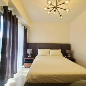 a bedroom with a large bed and a chandelier at INSPIRIA Condo Free Airport Pickup for 3 nights stay or more in Davao City +11 photos