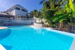 a large blue swimming pool in front of a white fence at Le Paille en Queue Résidence Touristique in Saint-Louis