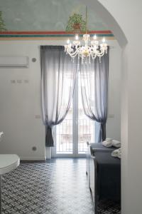 a bedroom with a chandelier and a large window at Zagara e Lumia in Catania