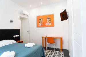 a bedroom with a bed and a desk and a painting at Zagara e Lumia in Catania
