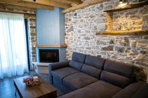 a living room with a couch and a stone wall at Guesthouse Iris in Tsagarada