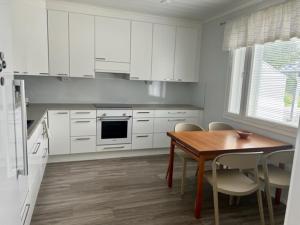 NärpiöにあるSoda Home - Hillside House - 24h check inの白いキャビネット、テーブルと椅子付きのキッチンが備わります。