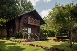 a log cabin with a balcony in a garden at Viewpoint - Cabin 5 in Haenertsburg