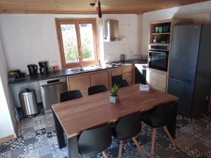 - une cuisine avec une table en bois et des chaises dans l'établissement Tres bel appartement dans une maison avec SPA, à Séez