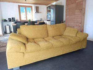 un sofá amarillo en una sala de estar con cocina en Tres bel appartement dans une maison avec SPA, en Séez