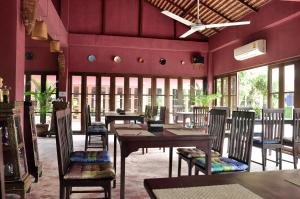 a dining room with tables and chairs and windows at Chiangmai Royal Creek Hotel in Hang Dong