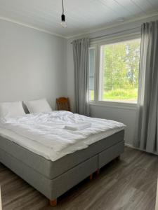 uma cama num quarto com uma grande janela em Soda Home - Hillside House - 24h check in em Närpiö