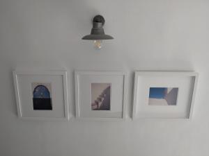 four pictures on a white wall with a lamp at Latmos 1860 in Skala