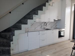 a kitchen with white cabinets and a staircase at Pajūrio Ąžuolo Istorija 10 in Palanga