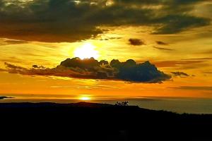 una puesta de sol sobre el océano con el sol escondido detrás de las nubes en Trieste for you with Nature&Hiking 