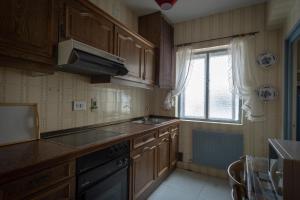 a kitchen with wooden cabinets and a sink and a window at Casa rural Arribes Vida in Vitigudino