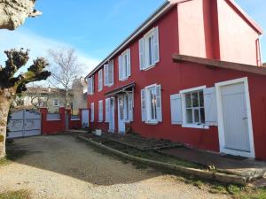 una casa roja con puertas blancas y un patio en Les lunettes d'Oyo 2 en Oyonnax