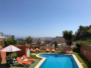 a pool on the roof of a house with chairs and an umbrella at Cozy rooms in terraced house in Fuengirola