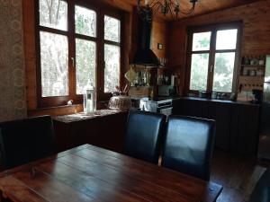 Ház a kishegyen في Felsőörs: طاولة وكراسي خشبية في مطبخ مع نوافذ