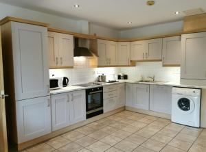 a kitchen with white cabinets and a washer and dryer at Erne View Apartments 1C - Lakeside Apartment Enniskillen in Enniskillen