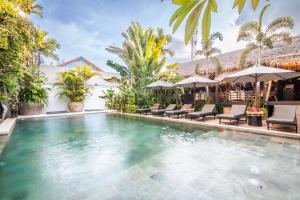 a pool at a resort with chairs and umbrellas at La Bastide de Caro in Siem Reap