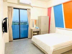 1 dormitorio con cama y ventana grande en Penghu Happy House, en Magong
