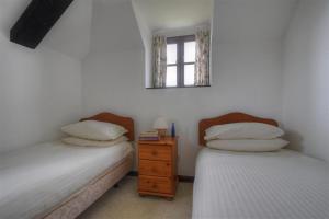 1 Schlafzimmer mit 2 Betten und einem Wandspiegel in der Unterkunft Rose Cottage in Musbury