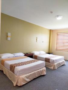 um quarto de hotel com duas camas e uma janela em MADISON PARK HOTEL em Tacloban