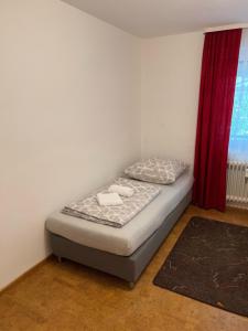 Esslingen am Neckar Württembergstraße 27 في Brühl: سرير صغير في غرفة ذات ستارة حمراء