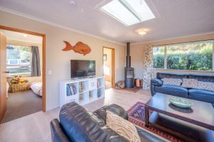 a living room with a leather couch and a television at Woodills Wonderland - Akaroa Holiday Home in Akaroa