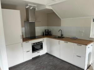 a kitchen with white cabinets and a sink at Villa Clementine with sauna in Ermelo in Ermelo