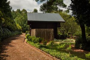 a building with a tin roof in a garden at Viewpoint - Cabin 6 in Haenertsburg
