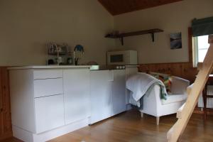 a kitchen with white cabinets and a microwave and a couch at Glamping Julared in Mullsjö