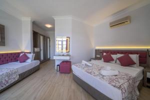 a hotel room with two beds and a pink suitcase at Lykia Botanika Beach Fun & Club - All Inclusive in Fethiye