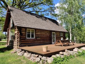 una baita di tronchi con una piattaforma di legno di fronte ad essa di Tiku Holiday Homes a Kiidjärve
