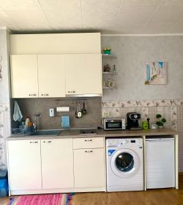 a kitchen with white cabinets and a washing machine at Apartament Keti in Nesebar