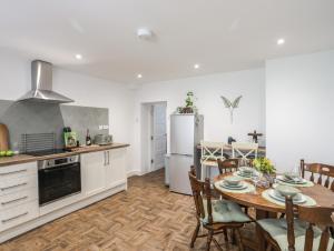 una cucina e una sala da pranzo con tavolo e frigorifero di Y Goedwig a Llanfairpwllgwyngyll