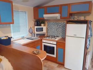 a kitchen with a white refrigerator and a stove at Mobil-home "Le pin bleu" à St-Paul-les-Dax in Mées