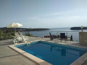 una piscina con mesa y sillas y el océano en Oliva Apartments Lozica, en Dubrovnik