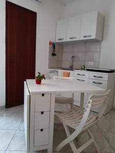 eine weiße Küche mit einem weißen Tisch und Stühlen in der Unterkunft Aria in Porto Santa Margherita