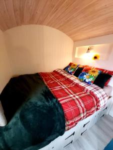 Cama en habitación con techo de madera en The Feathers Shepherds Hut, en Áth Eascrach