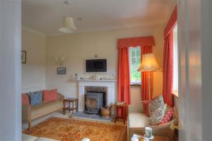 a living room with a fireplace and red curtains at Lynch Cottage in Rousdon