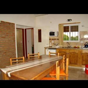 uma cozinha com uma grande mesa de madeira e cadeiras em Llanten Dorado Cabañas em Villa Giardino