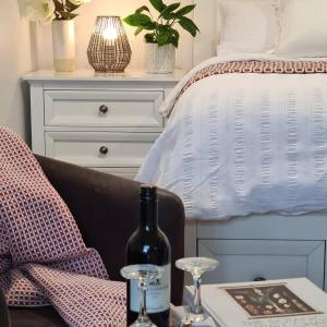 ein Schlafzimmer mit einem Bett und einem Tisch mit einer Flasche Wein in der Unterkunft Kadi House - Unit 2 in Wynyard