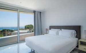 una camera con un letto bianco e una grande finestra di Apartamentos Marivent by Brava Hoteles a Platja  d'Aro