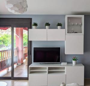 a living room with a tv and white cabinets at Espacioso apartamento de 2 dormitorios in Palm-mar