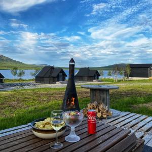 a picnic table with a fireplace and a glass of wine at Arctic Land Adventure Glass Igloos in Kilpisj&auml;rvi