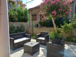 a patio with chairs and tables and a tree with pink flowers at Kuća za odmor Ljubica Šibenik in Šibenik