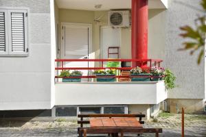 un banco de madera sentado en un balcón con macetas en Flowers Apartments, en Golem