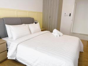 - un grand lit blanc avec une serviette dans l'établissement Ekocheras @ Kuala Lumpur, à Kuala Lumpur