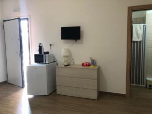 a room with a refrigerator and a tv on the wall at B&B Ornella in Leverano