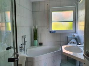 a white bathroom with a tub and a sink at Panorama Seesicht in Sipplingen