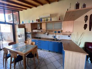 una cocina con armarios azules y una mesa con sillas en The Stylish House, en Adrano